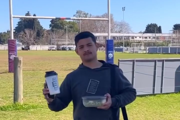 Un jugador en la cancha muestra su shaker de proteína y su tupper para después del partido