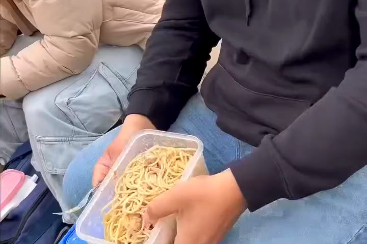 Un jugador con un tupper de fideos, almorzando en la cancha antes del partido